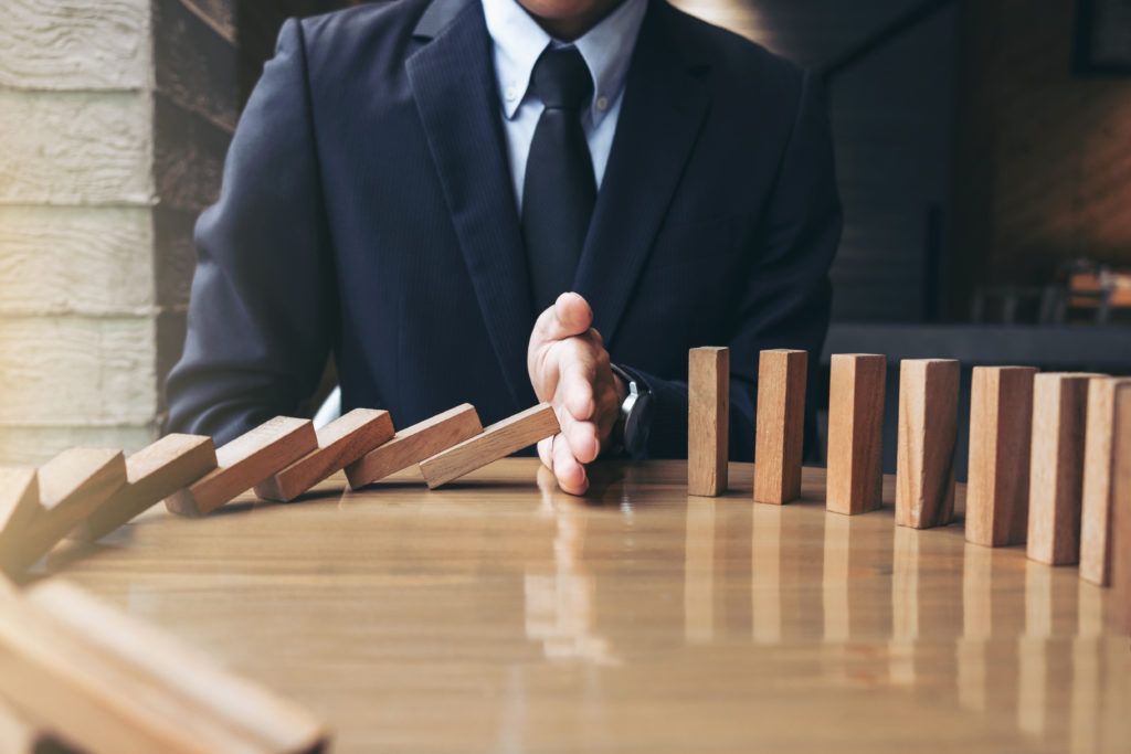 A hand stopping a row of falling wooden blocks on a table