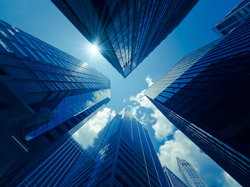 Looking up at glass skyscrapers against a blue sky
