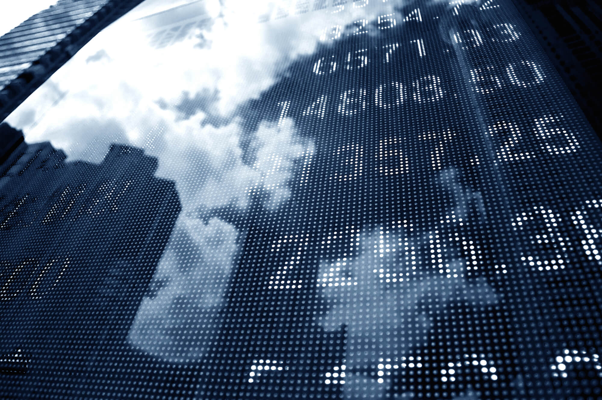 Stock market ticker board reflecting the sky